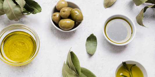 Green olives and bowls of extra virgin olive oil with olive leaves